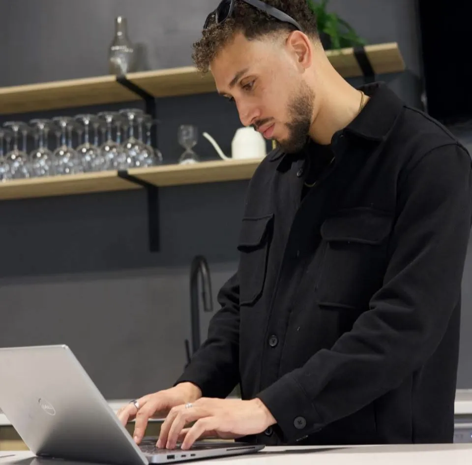 Riyad, software engineer and founder of Elite Profits Inc., working on a laptop